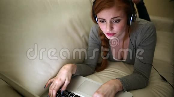 美丽的黑发女人躺在床上听音乐视频的预览图