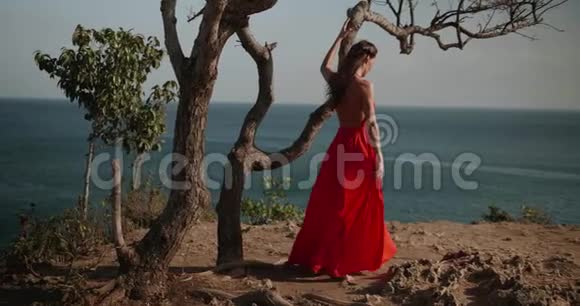 美丽的女人穿着红色的衣服在海边的悬崖上视频的预览图