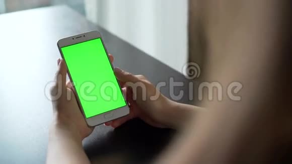 年轻女性使用带有绿色屏幕的智能手机进行交流视频的预览图