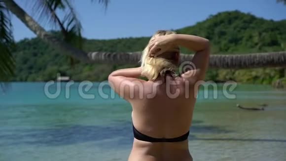 海滩上穿粉色泳装的年轻女子视频的预览图