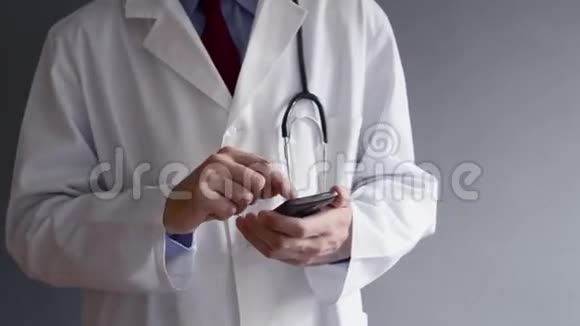 身穿白大褂的男医生正在使用现代智能手机视频的预览图