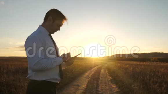 人类的双手正把手指压在平板电脑上男人检查电子邮件在公园日落时分工作的商人视频的预览图