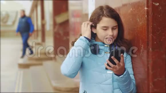 少女在地下地铁生活方式乘坐地铁等待火车的到来手持智能手机视频的预览图