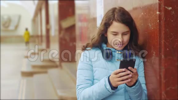 少女在地下地铁中乘坐地铁的生活方式等待火车的到来手持智能手机视频的预览图
