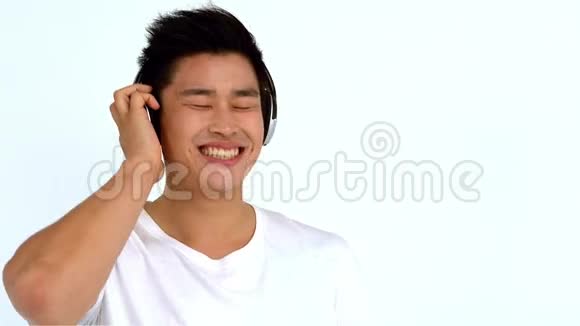 微笑亚洲男人带着耳机听音乐视频的预览图