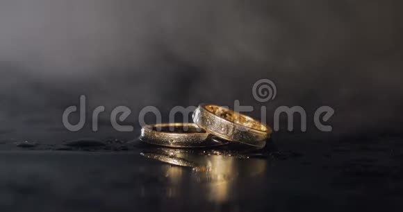 婚礼戒指躺在黑暗的水面上闪闪发光关闭宏水中的环对反思视频的预览图