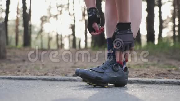 漂亮的女孩收紧了道路鞋并在训练比赛前戴上自行车眼镜单车概念视频的预览图
