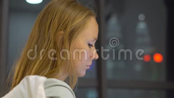 一位年轻女士用笔记本电脑工作她坐在床上背着一个背景的摩天轮的轮廓视频的预览图