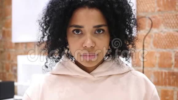 一位严肃的非裔美国妇女在白色背景的摄影棚里看镜头视频的预览图