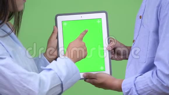 年轻的亚洲商界情侣一起使用数码平板电脑视频的预览图