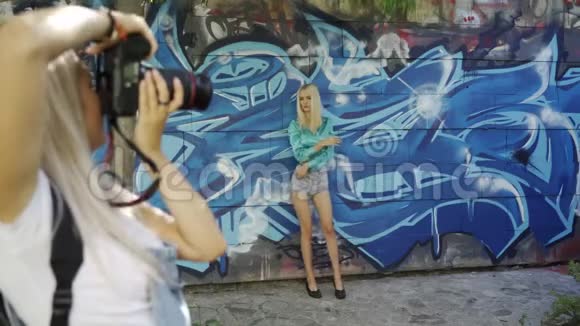 金发女郎用涂鸦向墙上的摄影师摆姿势视频的预览图