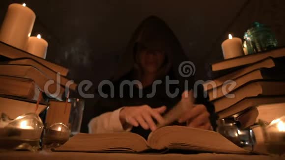 中等特写的女孩魔术师在一个黑暗的房间在烛光和寻找一个法术翻书低视频的预览图