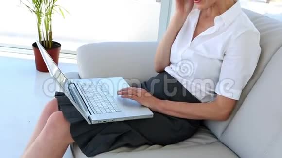 女商人坐在沙发上用手提电脑打电话视频的预览图