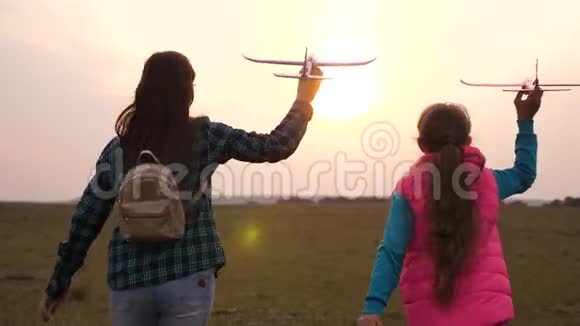 快乐的女孩姐妹在田野日落时带着玩具飞机跑幸福家庭的概念孩子们玩玩具视频的预览图