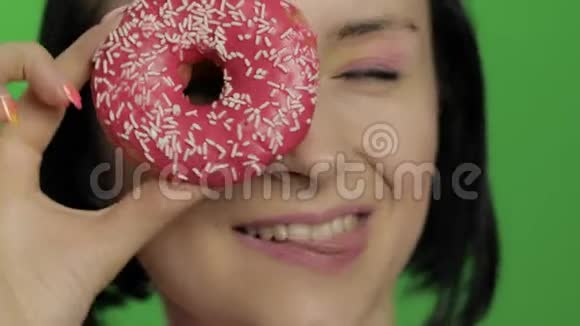 快乐美丽的小女孩摆姿势和玩甜甜圈彩色键视频的预览图