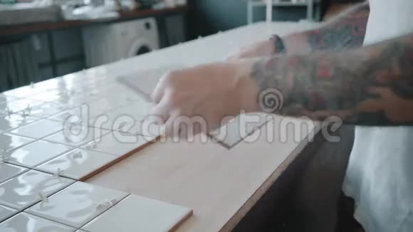 纹身男在厨房餐桌上铺瓷砖视频的预览图