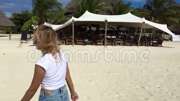 一个迷人的女孩沿着海滩散步用相机调情慢动作视频的预览图