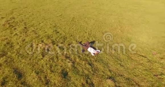 低轨道飞行围绕着绿草上的人与笔记本垫在黄色的农村田野视频的预览图