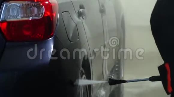 洗车机清洗汽车一个洗车工人用水洗一辆车特写镜头视频的预览图