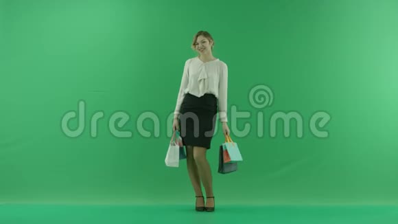 带着购物袋的漂亮购物女人女购物者拿着购物袋在绿色背景前的工作室视频的预览图