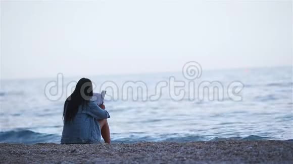 在热带白色海滩读书的年轻女子视频的预览图
