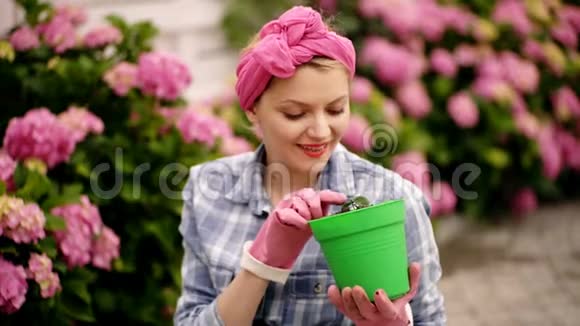 快乐的女人花匠护花和浇水土壤和肥料女人在花园里照料鲜花视频的预览图