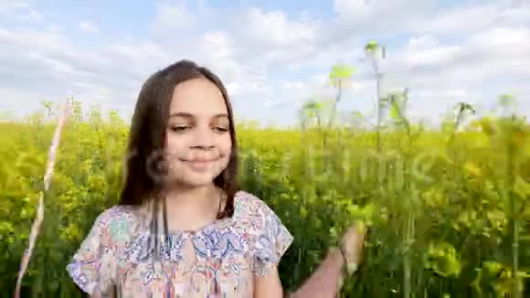 穿着裙子的小女孩手里拿着气球穿过黄色的麦田缓慢的动作视频的预览图