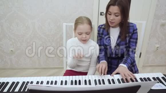 年轻的女老师和小女孩一起弹钢琴视频的预览图