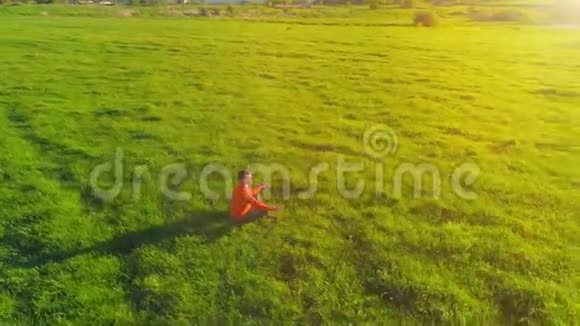 低空径向飞行超过运动瑜伽男子在完美的绿草在山上日落视频的预览图
