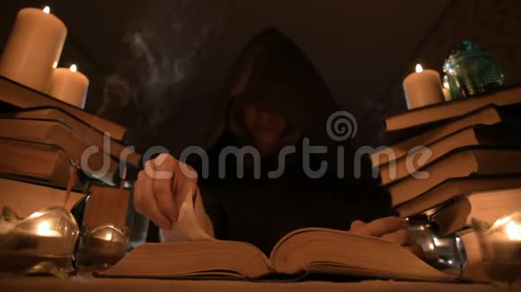 中等特写的女孩魔术师在一个黑暗的房间在烛光和寻找一个法术翻书低视频的预览图
