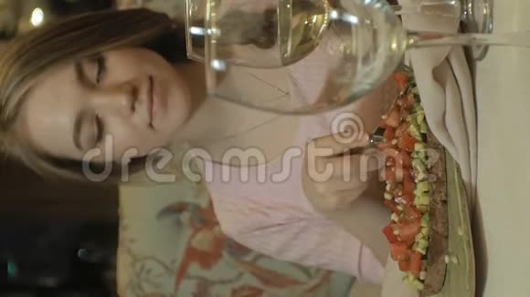 垂直视频美丽的金发女人在餐厅吃喝午休视频的预览图