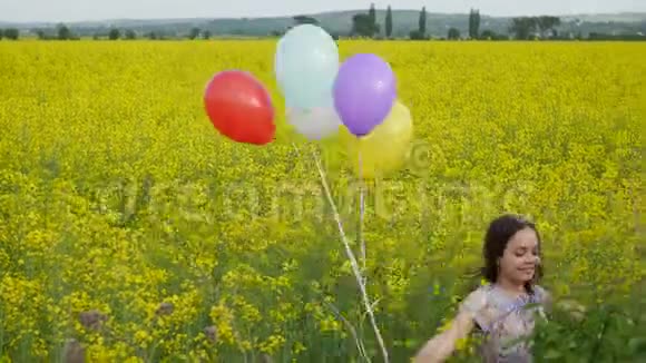 穿着一件连衣裙的小女孩手里拿着气球穿过黄色的麦田视频的预览图