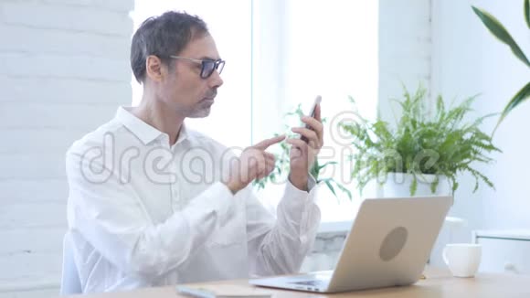 男人在智能手机上浏览互联网视频的预览图