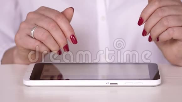 穿着白色衬衫的女人看着平板电脑上的信息女商人在办公室或家里工作打字视频的预览图