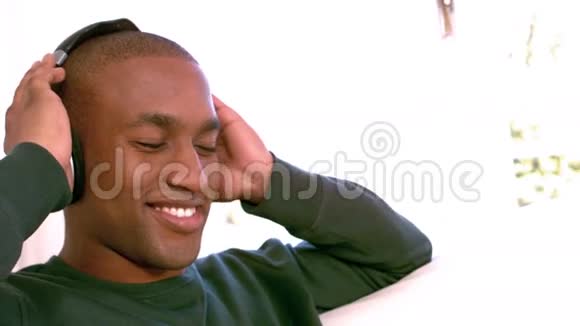 微笑的男人在沙发上听音乐视频的预览图