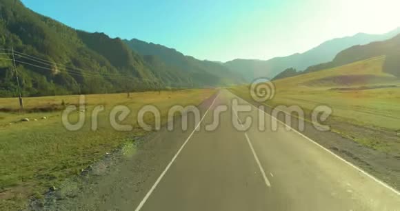 在阳光明媚的夏季早晨低空飞越山路和草地视频的预览图