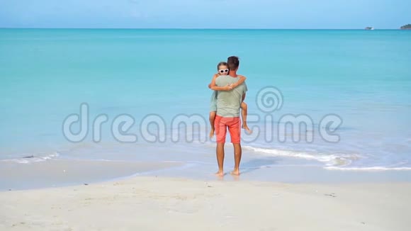 快乐的父亲和他可爱的小女儿一起在热带海滩散步视频的预览图