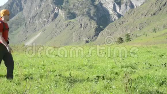 徒步旅行者带着背包在绿色的山地草地上行走夏季运动和娱乐理念视频的预览图