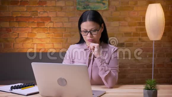 在办公室室内用笔记本电脑打字的成年亚洲女商人特写镜头视频的预览图