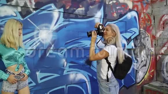 金发女郎用涂鸦向墙上的摄影师摆姿势视频的预览图