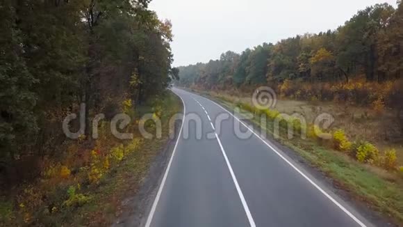 秋季森林环绕的道路上的汽车鸟瞰图视频的预览图