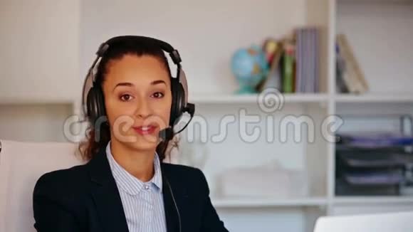 带耳机和笔记本电脑的女孩在办公室接电话视频的预览图