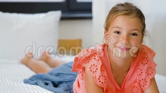 幸福的微笑美丽的女孩躺在家里的床上视频的预览图
