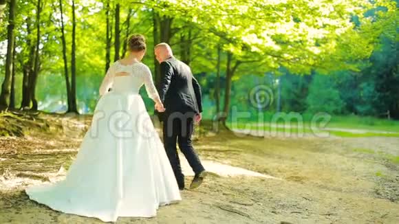 新郎新娘在森林里散步的夫妇视频的预览图