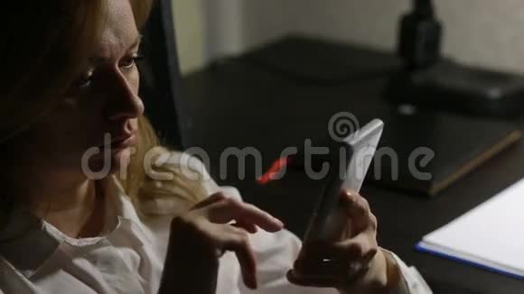 女人坐在办公室的桌子上在智能手机上写信息视频的预览图