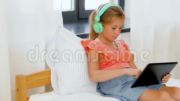 戴着耳机听平板电脑音乐的女孩视频的预览图