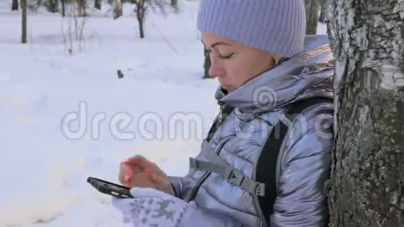 女人在树林里散步旅行者在森林的电话里被拍照女孩做自拍和沟通视频的预览图