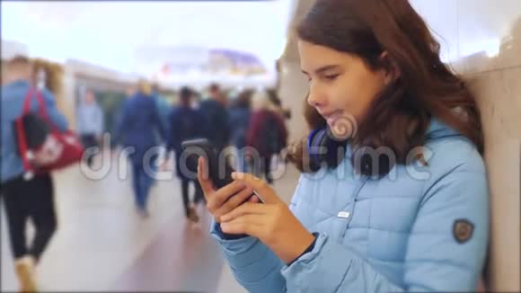 十几岁的女孩带着智能手机和耳机等待地铁很多人聚集在地下地铁地下生活方式视频的预览图