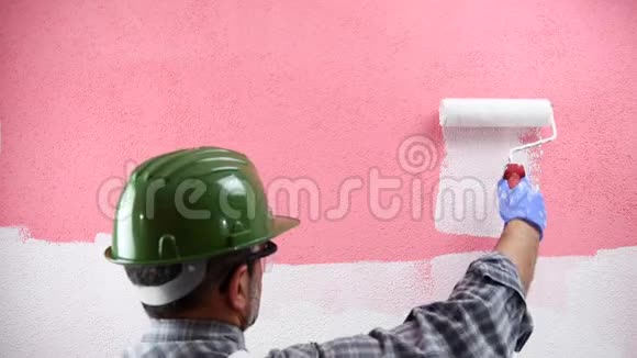 房子画家工人用白色油漆粉刷粉红色的墙建筑视频的预览图