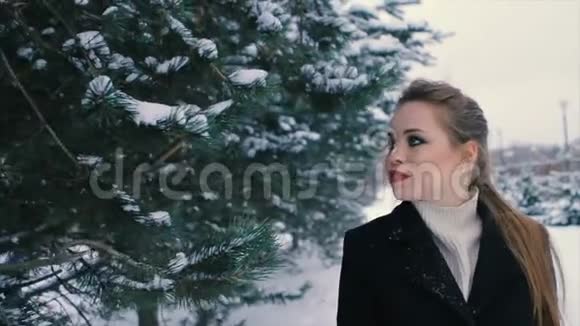 布鲁内特富婆穿着黑色外套在圣诞树的背景下慢动作视频的预览图
